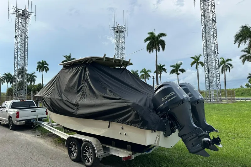 Slide: The Image of 2011 Grady-White Freedom 275 boat on trailer, covered, with Yamaha engines, near palm trees. - 32