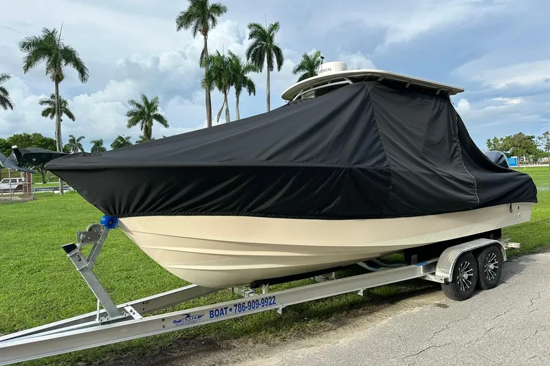 Slide: The Image of 2011 Grady-White Freedom 275 boat covered on trailer, parked near palm trees. - 33