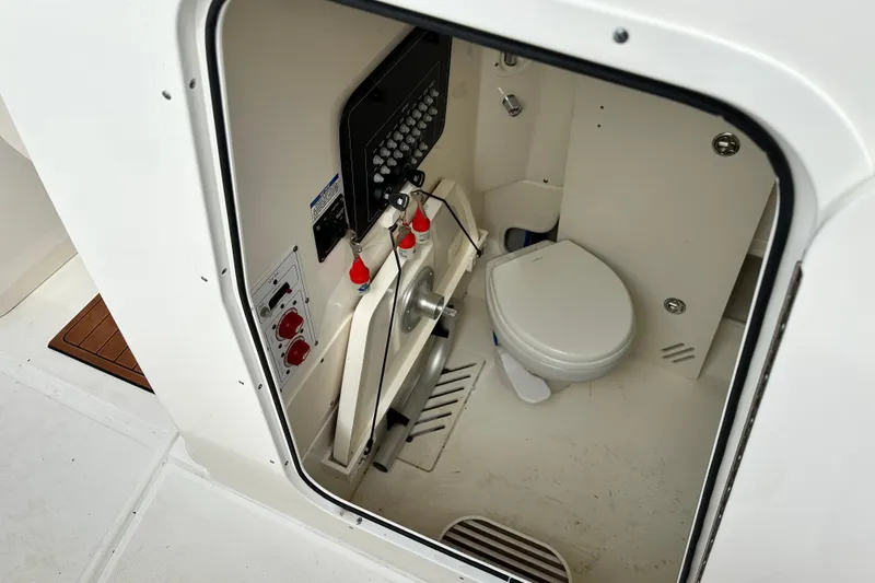 Slide: The Image of 2024 Boston Whaler 250 Outrage boat interior with marine toilet and control panel. - 13