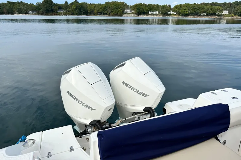 Slide: The Image of 2024 Boston Whaler 250 Outrage with twin Mercury outboard engines on calm water. - 16
