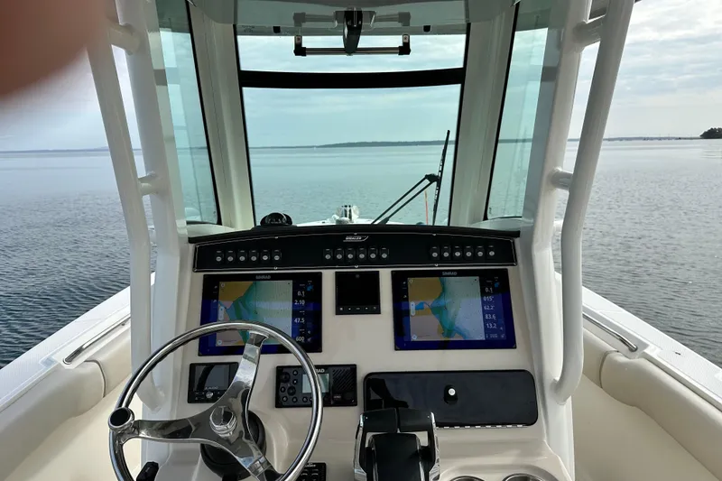 Slide: The Image of 2024 Boston Whaler 250 Outrage helm with dual navigation screens on calm water. - 6