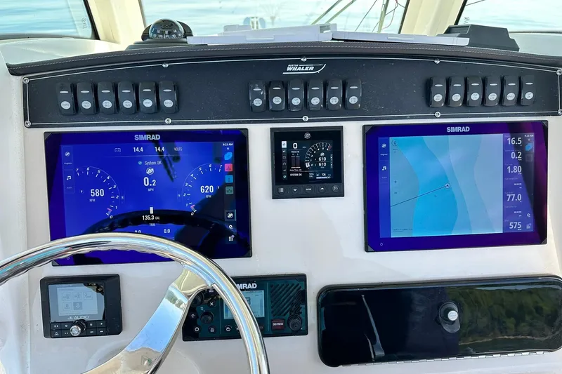 Slide: The Image of 2024 Boston Whaler 250 Outrage dashboard with Simrad navigation displays and controls. - 7