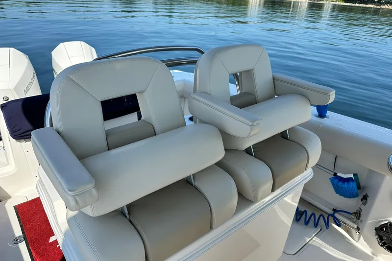 Slide: The Image of 2024 Boston Whaler 250 Outrage boat seats with armrests on calm water. - 8
