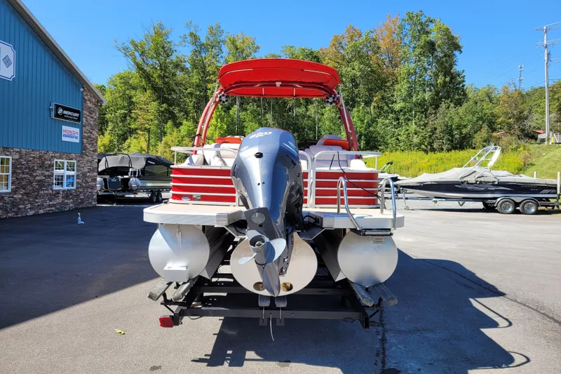 Slide: The Image of 2014 Bennington G23 pontoon boat with outboard motor, parked near marine dealership. - 3