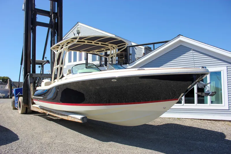 Slide: The Image of 2017 Chris-Craft Calypso 26 boat on forklift near building, clear sky background. - 0