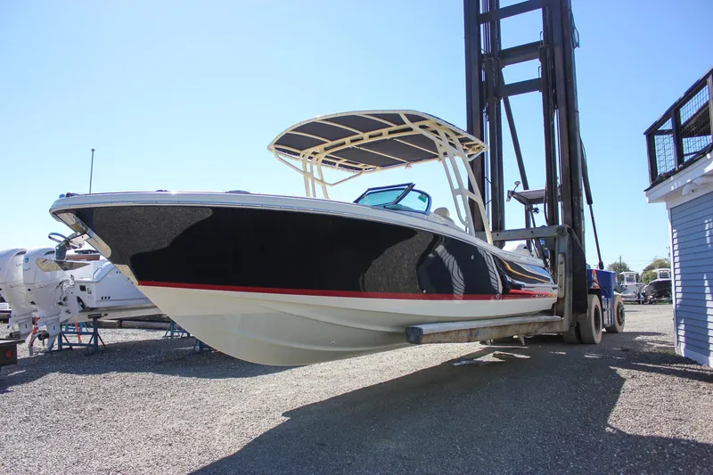 Slide: The Image of 2017 Chris-Craft Calypso 26 boat lifted by forklift in a marina setting. - 1