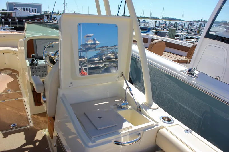 Slide: The Image of 2017 Chris-Craft Calypso 26 boat interior with helm, sink, and marina view. - 13