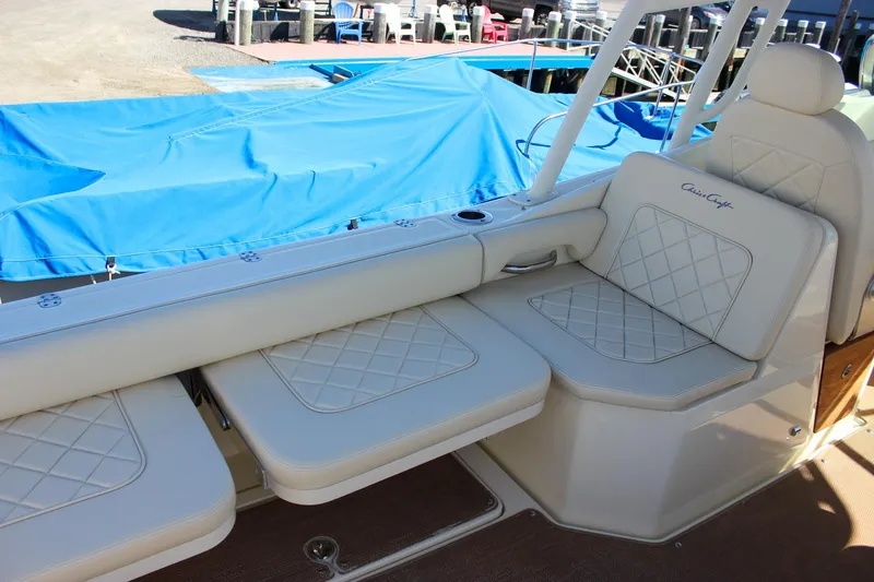 Slide: The Image of 2017 Chris-Craft Calypso 26 boat interior with beige cushioned seating and blue cover. - 19
