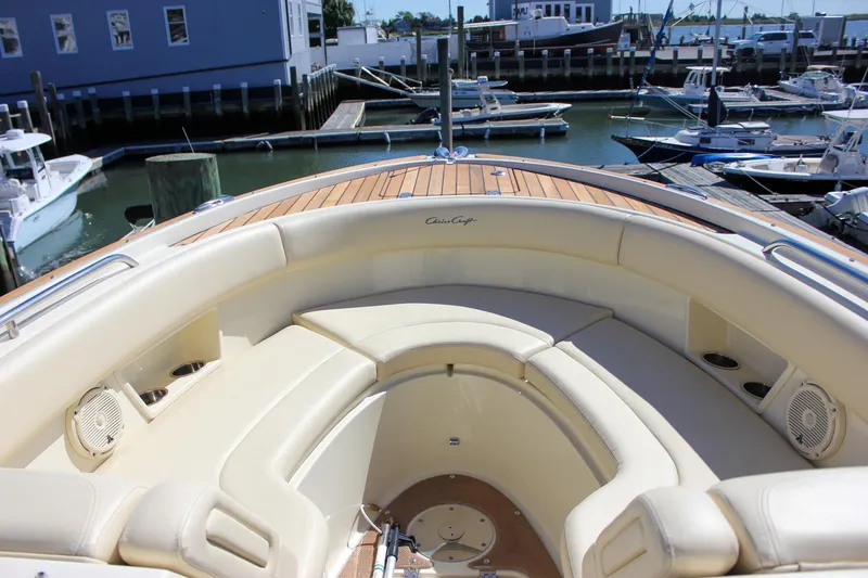 Slide: The Image of 2017 Chris-Craft Calypso 26 boat interior with beige seating and wooden deck in marina. - 37