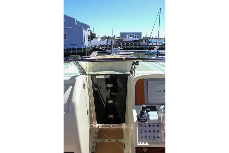 Slide: The Image of 2017 Chris-Craft Calypso 26 boat interior with control panel and marina view. - 44