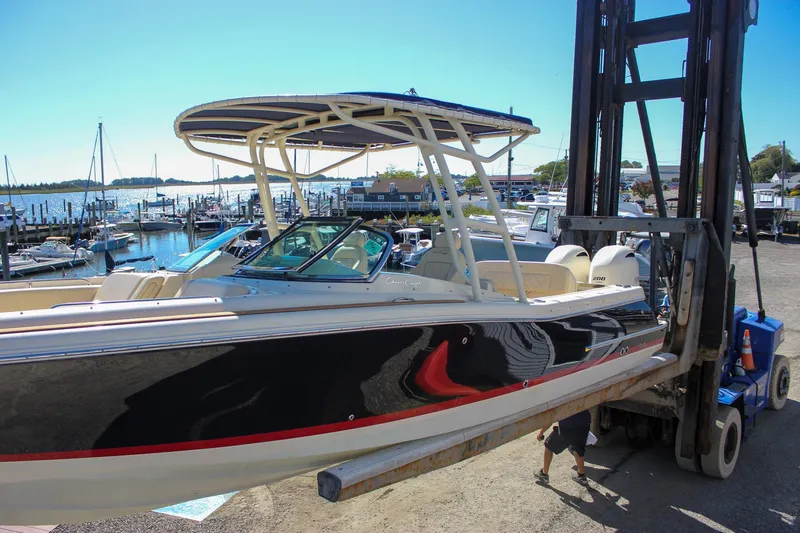 Slide: The Image of 2017 Chris-Craft Calypso 26 boat lifted at marina with scenic waterfront background. - 56