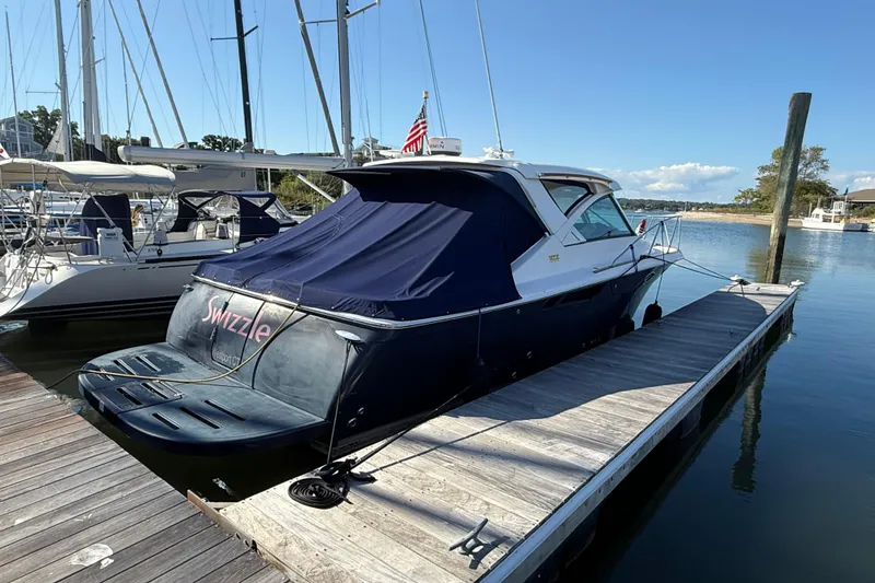 Slide: The Image of 2012 Tiara Yachts 3100 Coronet docked, covered, with American flag, sunny marina setting. - 1