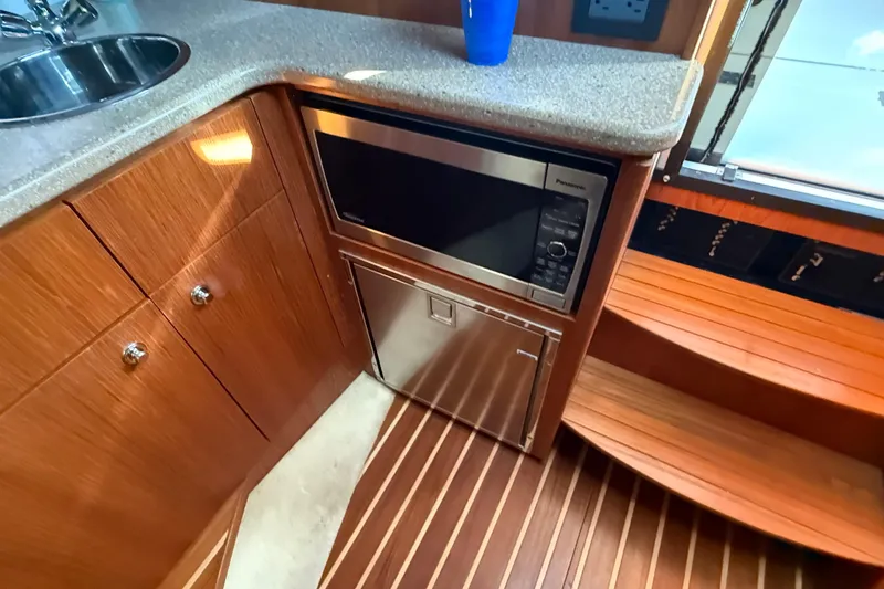 Slide: The Image of 2012 Tiara Yachts 3100 Coronet interior with microwave, sink, and wooden cabinetry. - 23