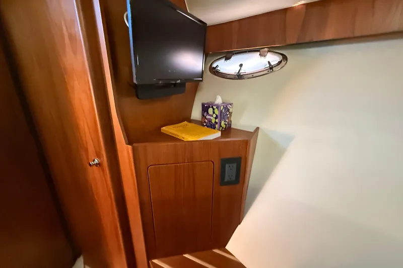 Slide: The Image of Interior of 2012 Tiara Yachts 3100 Coronet with TV, porthole, and wooden cabinetry. - 24