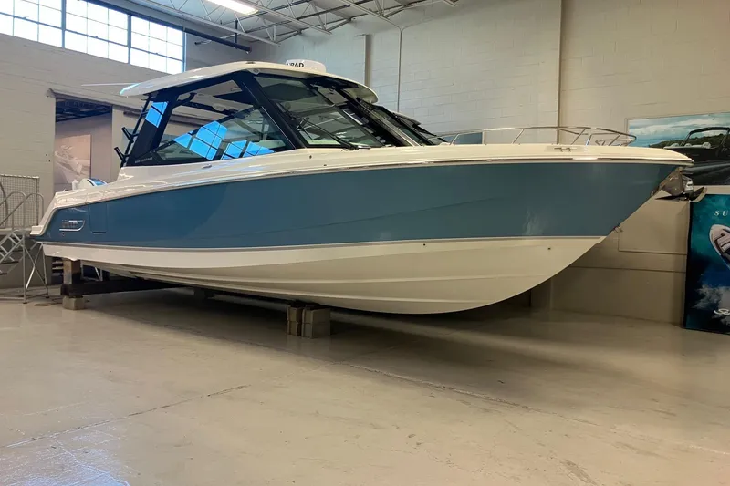 Slide: The Image of 2026 Boston Whaler 330 Vantage boat in showroom, blue and white exterior. - 1