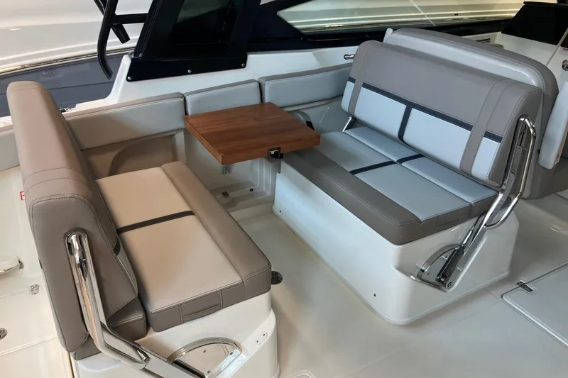 Slide: The Image of 2026 Boston Whaler 330 Vantage interior seating with a wooden table. - 15