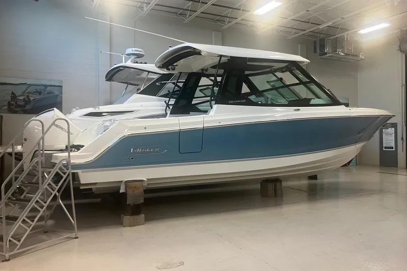 Slide: The Image of 2026 Boston Whaler 330 Vantage boat in showroom, blue and white exterior. - 3