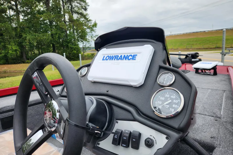 Slide: The Image of 2026 Ranger RT178 boat dashboard with Lowrance display and gauges, surrounded by lush greenery. - 11