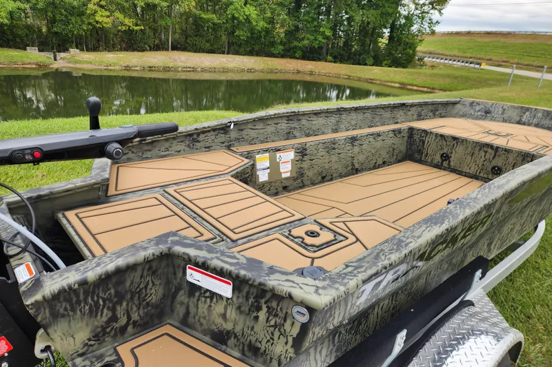 Slide: The Image of 2026 Tracker Grizzly 1650 T Prairie Wings Edition boat by a serene pond. - 12