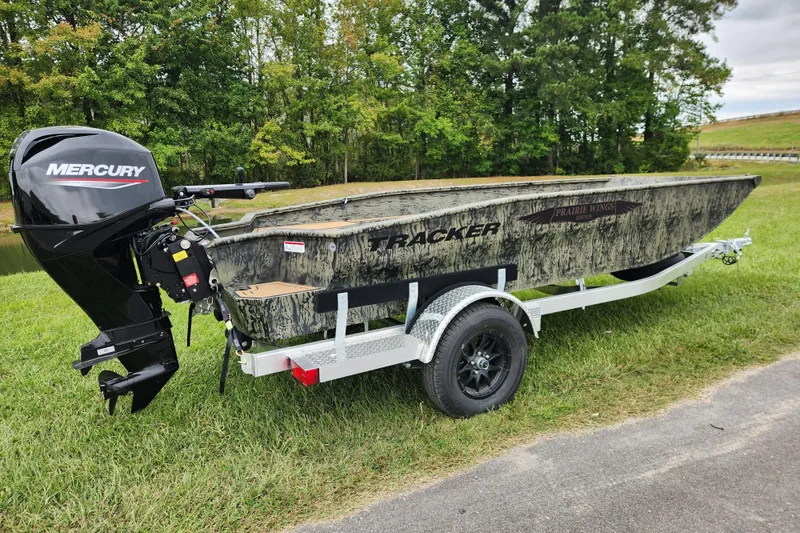 Slide: The Image of 2026 Tracker Grizzly 1650 T Prairie Wings Edition boat on trailer, Mercury motor, outdoors. - 2