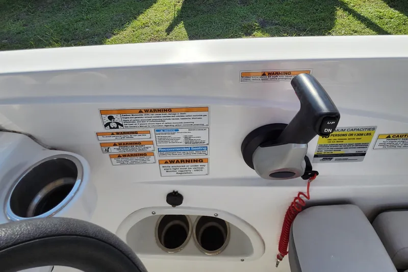 Slide: The Image of 2023 Hurricane SunDeck Sport 205 OB control panel with warning labels and throttle lever. - 12