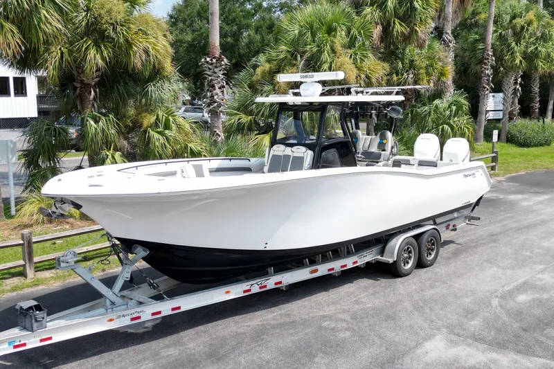 The Image of 2020 Tidewater 320 CC Adventure boat on trailer, surrounded by palm trees. - 0