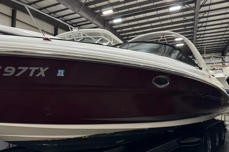 Slide: The Image of 2006 Sea Ray 290 Select EX boat in indoor storage, maroon and white exterior. - 3