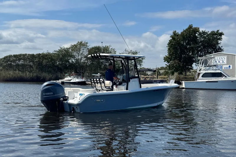 Slide: The Image of 2022 Sea Hunt Ultra 219 boat on calm water with Yamaha engine, trees, and dock in background. - 1