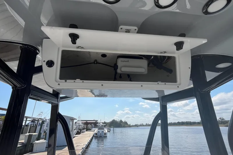 Slide: The Image of 2022 Sea Hunt Ultra 219 boat console with open storage compartment, dockside view. - 12