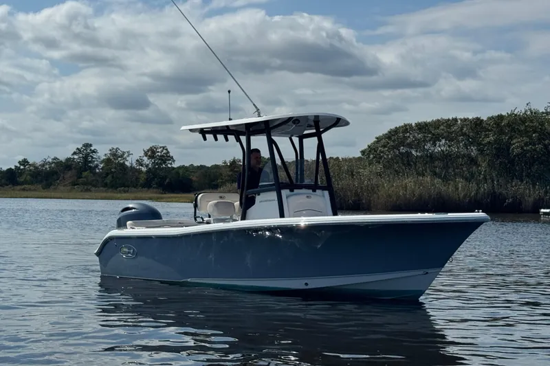 Slide: The Image of 2022 Sea Hunt Ultra 219 boat on calm water under cloudy sky. - 16