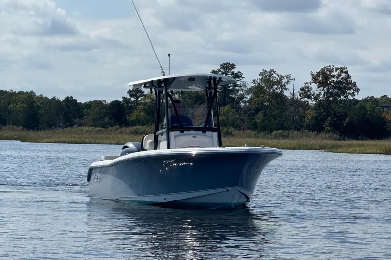 Slide: The Image of 2022 Sea Hunt Ultra 219 boat cruising on a calm river with trees in the background. - 17
