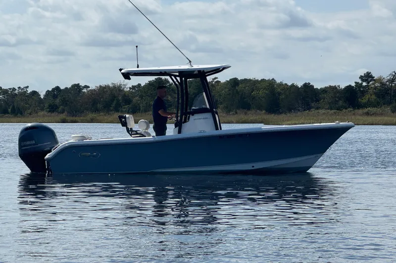 Slide: The Image of 2022 Sea Hunt Ultra 219 boat on calm water with Yamaha engine, under a cloudy sky. - 18