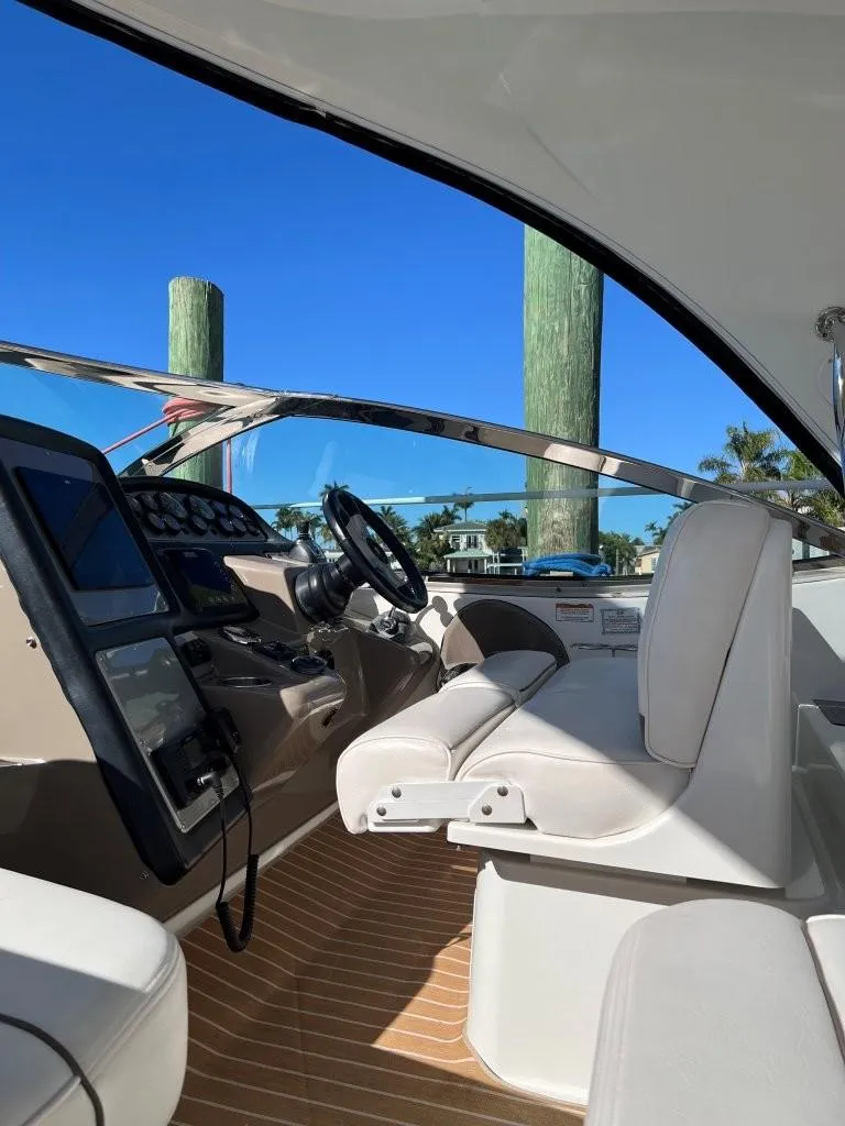 Slide: The Image of 2008 Cruisers 420 Express helm with modern controls and white seating, docked under clear blue sky. - 7