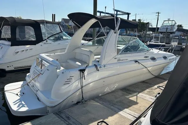 Slide: The Image of 2004 Sea Ray 260 Sundancer boat docked at marina, featuring sleek white design and canopy. - 3