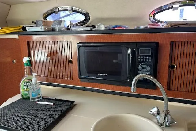 Slide: The Image of 2004 Sea Ray 260 Sundancer interior with microwave, sink, and wooden cabinetry. - 9