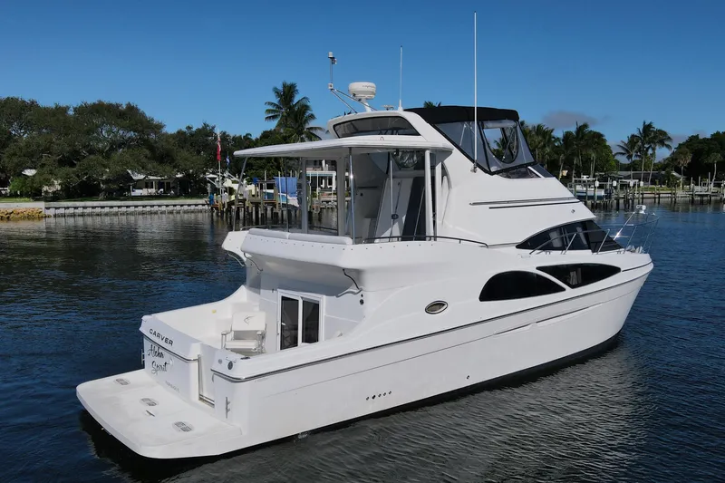 Slide: The Image of 2005 Carver 41 Cockpit Motor Yacht on calm water, surrounded by lush greenery. - 1