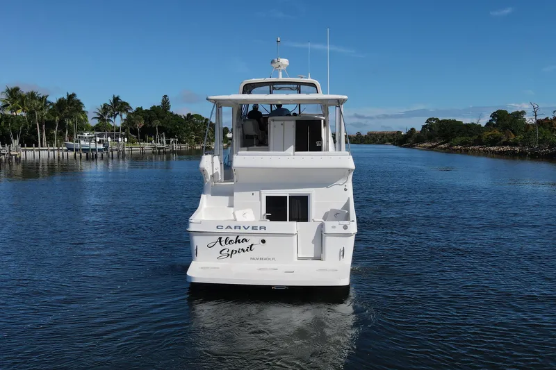 Slide: The Image of 2005 Carver 41 Cockpit Motor Yacht on a serene waterway, surrounded by lush greenery. - 2