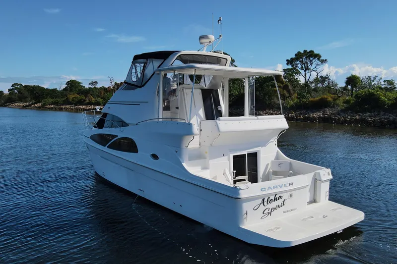 Slide: The Image of 2005 Carver 41 Cockpit Motor Yacht on serene water, surrounded by lush greenery. - 3