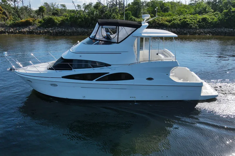 Slide: The Image of 2005 Carver 41 Cockpit Motor Yacht cruising on calm water, surrounded by lush greenery. - 4