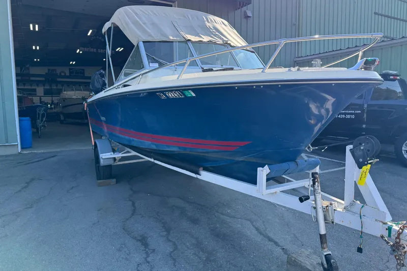 The Image of 1975 Century Raven boat with blue hull and red stripe on trailer. - 0