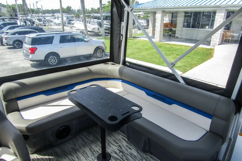 Slide: The Image of Interior of 2025 Armada v17 boat with seating and table, parked cars visible outside. - 8
