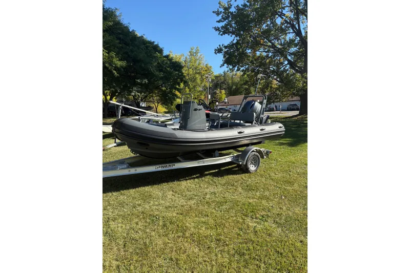The Image of 2025 Highfield Patrol 500 boat on trailer, parked on grass under trees. - 0