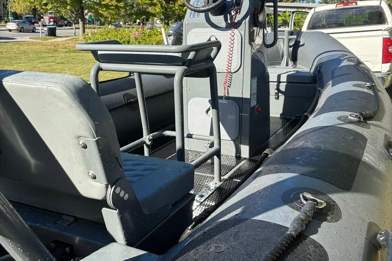 Slide: The Image of 2025 Highfield Patrol 500 boat interior with seating and control console, parked outdoors. - 3