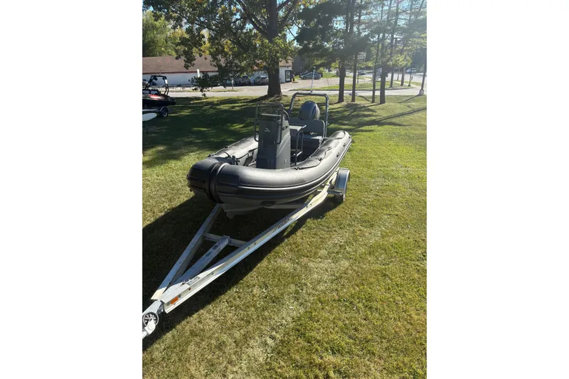 Slide: The Image of 2025 Highfield Patrol 500 boat on trailer, parked on grassy area under trees. - 4