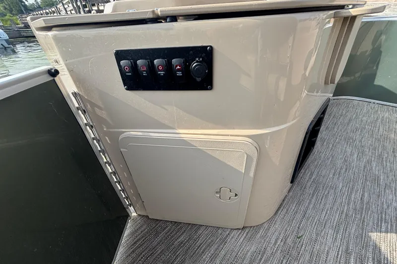 Slide: The Image of 2024 Godfrey SW2286FS boat control panel with switches and storage compartment. - 10