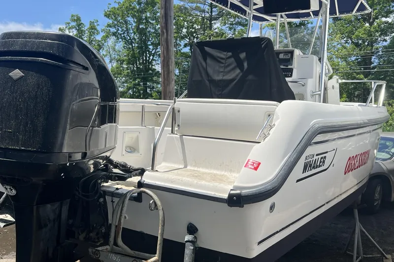 Slide: The Image of 2002 Boston Whaler 21 Outrage boat with outboard motor, docked outdoors. - 3