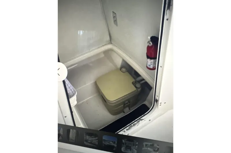Slide: The Image of 2002 Boston Whaler 21 Outrage interior with portable toilet and fire extinguisher. - 9