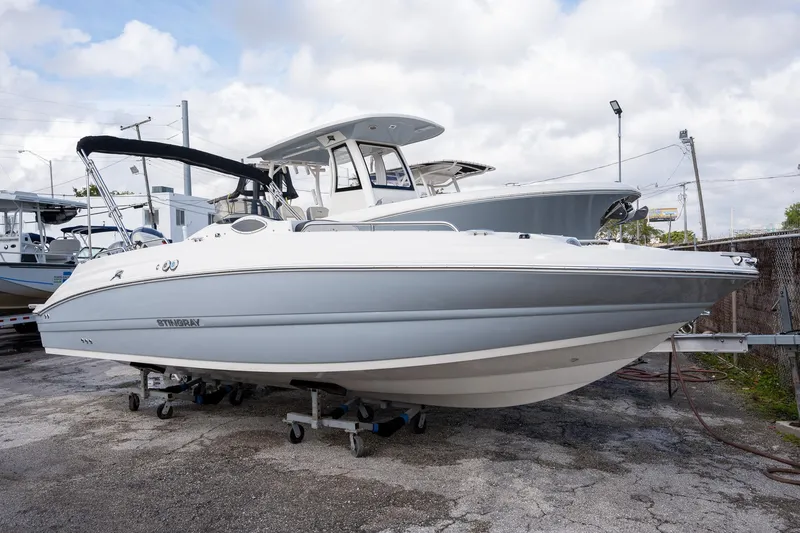 The Image of 2024 Stingray 212SC boat displayed outdoors on a trailer under cloudy skies. - 0