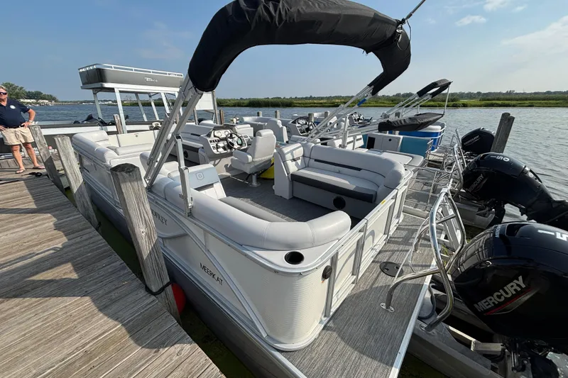 Slide: The Image of 2024 Godfrey Sw2286SB pontoon boat docked, featuring spacious seating and Mercury outboard engines. - 2