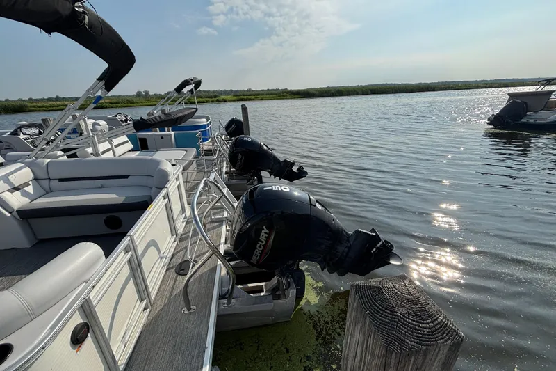 Slide: The Image of 2024 Godfrey Sw2286SB pontoon boat with Mercury outboard engines docked on a sunny day. - 5